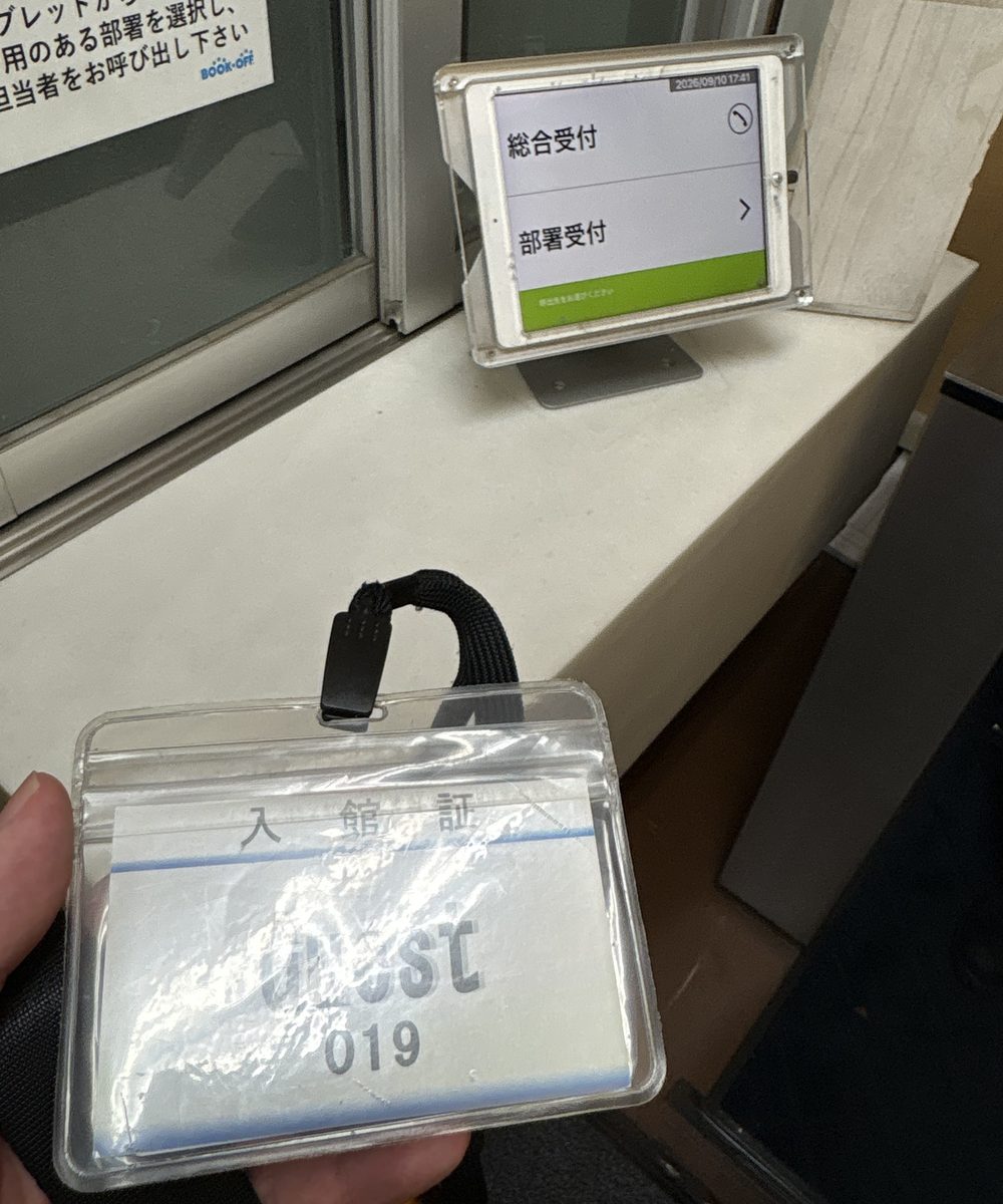 入口事務所の受付。窓口に受付用のタブレットが設置され、手前に入館証が置かれている